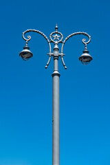 Fototapeta na wymiar Antique pillar with two lanterns against the blue sky.
