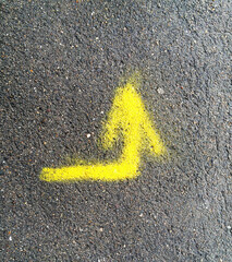 Yellow arrow on the asphalt, painted with paint