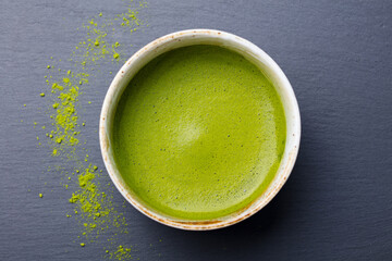 Matcha, green tea in a chawan cup. Grey stone background. Close up. Top view.