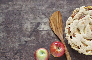 Round homemade Apple pie. Apple Charlotte close up with apples on a wooden background.Rustic style.