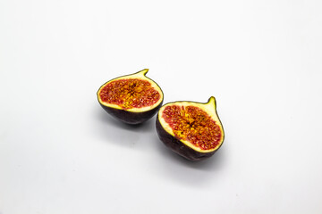 Two halves of figs isolated on a white background. View of ripe purple violet figs. The fig from...