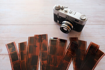 Vintage, retro analog film photo camera and filmstrips arranged on a wooden background, top view 