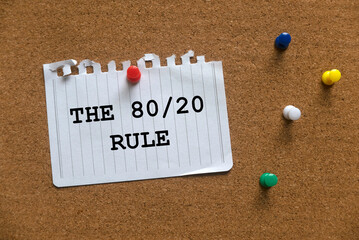 A colorful push pins and paper written with The 80/20 Rule on a cork board.