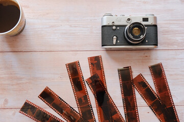 Retro camera, filmstrips, and a cup of coffee on a wooden background