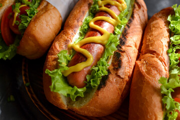 Hot dogs with various fillings. Dark background. food background with copy space. Hot dogs with mustard and ketchup, lettuce, cheese and tomatoes. Close up
