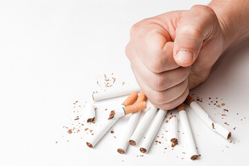Quit smoking concept: man smashes some cigarettes with his fist