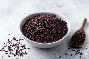 Black wild rice in a bowl. Grey stone background. Close up.