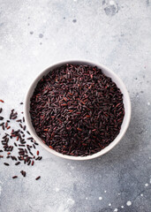 Black wild rice in a bowl. Grey stone background. Top view.