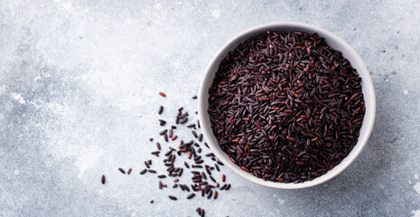 Black wild rice in a bowl. Grey stone background. Copy space. Top view.