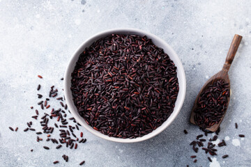 Black wild rice in a bowl. Grey stone background. Close up. Top view.