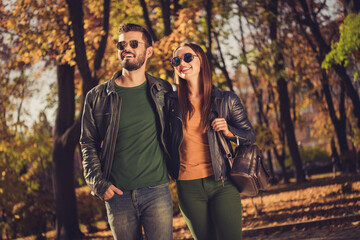 Photo of positive charming couple girl guy look aside in fall september city center park wear rucksack
