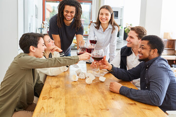 Lachende Freunde sagen Prost mit Glas Wein am Esstisch