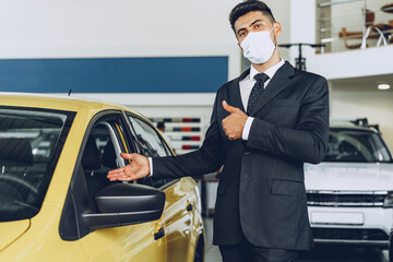 Man car dealer wearing protective medical mask on his working place