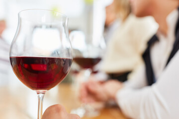 Glas Rotwein im Restaurant vor Gruppe Freunde beim Essen
