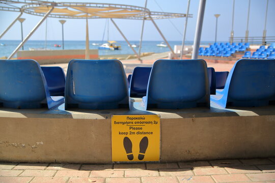 Bleu empty seats on outdoor theatre with yellow information keep 2 meters distance of COVID-19