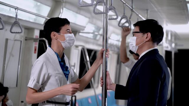 Business Man And Woman In Face Masks Greeting Each Other In Train Metro Subway Transport. Conscious Business People Touching Elbows To Avoid Contact. Contactless Hello On Covid-19 For New Normal Life.