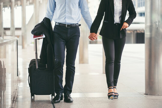 Businessman and Businesswoman Dragging suitcase luggage bag, walking to passenger boarding in Airport. Couple of love travel to work. Asian tourist wearing black suit pull trolley bag. Business Travel