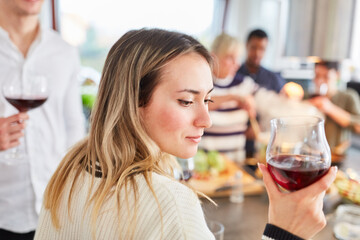 Junge Frau mit Glas Rotwein vor Freunden in Küche