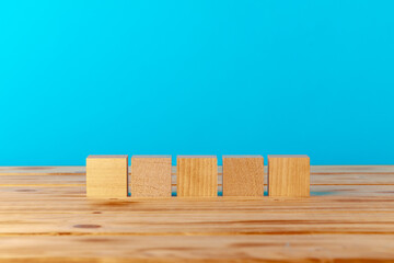 Stacked wooden blocks on wooden desk against blue background