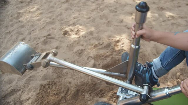 A Child Shovels Sand Using Toy Metal Excavator On The Playground During Summer. - Close Up Shot