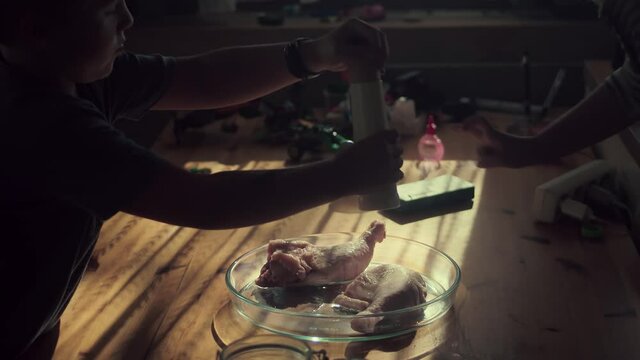 Seasoned The Chicken Legs At The Microwavable Glassware Using A Wooden Pepper Mill Grinder. - Wide Shot