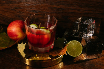 Autumn whisky cocktail with apple, lime and ice on the table in restaurant