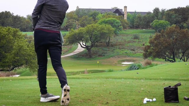 Golfer hits shot close to pin next to hole practicing on par 3 golf course on foggy day slow push in