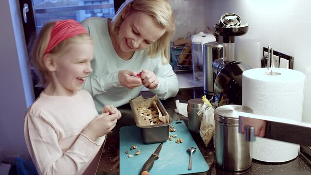 Mother and cute son baking together. They are decorating banana bread and have great time.