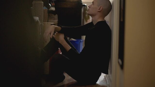 Lonely Man In Black Outfit Sitting Alone At The Corner Leaning Back On The Wall - Medium Shot