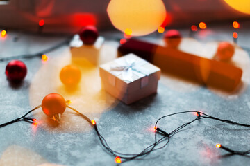 Christmas balls and white vinous gift boxes form the decoration of the Christmas tree, in the background in the form of a bokeh you can see colorful lights typical of the holiday season