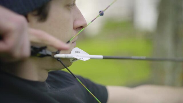 A close up shot of the fletching of an arrow as the compound bow is drawn and fired with the release aid.