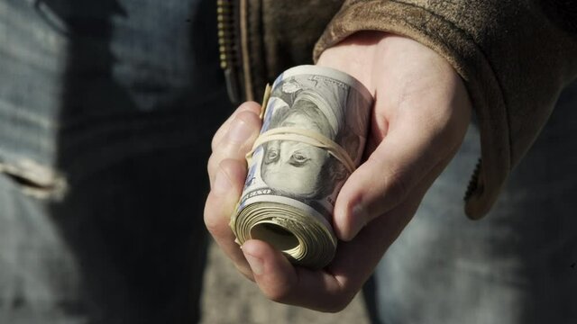 Man Holds Big Roll of Money, Puts it Away, Outside, Sunny Day, Closeup