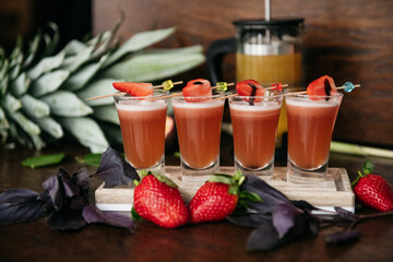 Strawberry shot cocktails set with basil on the stone board on the table in restaurant