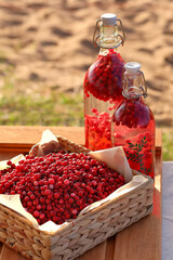 Cranberry juice in a bottle next to a basket on a wooden tray.