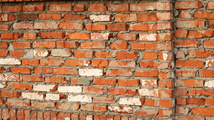 aging red street brick wall with destroyed surface and masonry irregularities, cracks and bulges of retro space