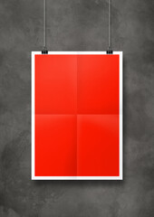 Red folded poster hanging on a concrete wall with clips