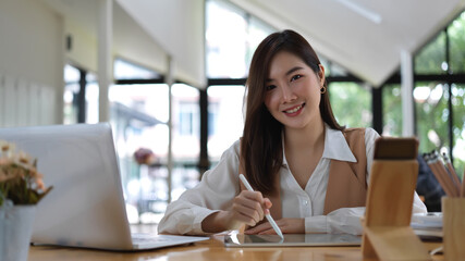 Female university student smiling and looking into camera while doing homework