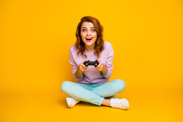 Full size photo of impressed crazy funny woman rest relax sit legs crossed play video games enjoy holiday wear stylish jumper gumshoes isolated over shine color background