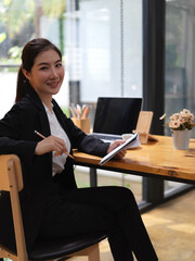 Businesswoman holding schedule book while sitting at worktable