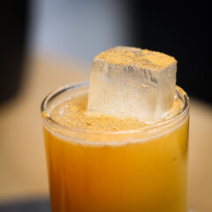 Voodoo cocktail in Highball glass on wood table , close up with ice chunk and cinnamon