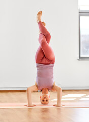 fitness, people and healthy lifestyle concept - young woman doing yoga in supported headstand at...