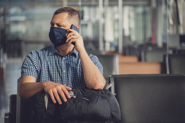 Man with a mask talking on mobile phone in airport lounge