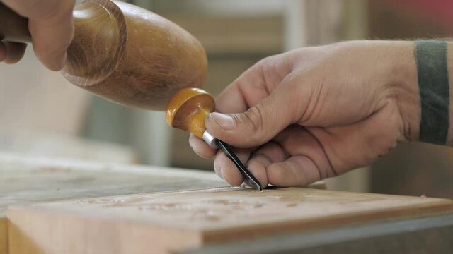 close-up. carpenter makes wood carving with a chisel and mallet. Carpentry, craftsmanship, design, manufacturing concept.