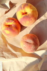 Three juicy, ripe and sweet peaches on wrapping paper. Seasonal summer fruits.