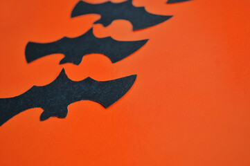 Black paper bats lie on an orange background.