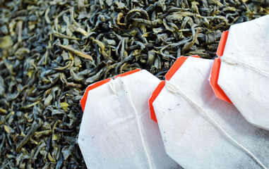 Tea bags lie on a heap of tea on a wooden background.