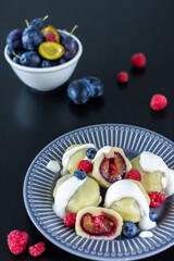 Dumplings with plums and raspberries and fruit in the background