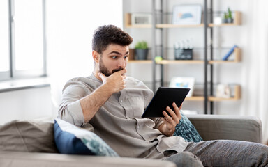 technology, people and lifestyle concept - shocked man with tablet pc computer at home