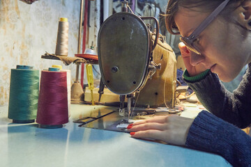 Woman tailor using retro sewing machine at home, hobby concept.