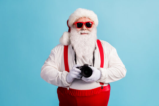 Portrait of his he nice attractive cheerful white-haired Santa father holding in hands professional cam shooting snap shot cadre focus isolated bright vivid shine vibrant blue color background